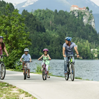 Štiričlanska družina na kolesu veselo kolesari ob Blejskem jezeru