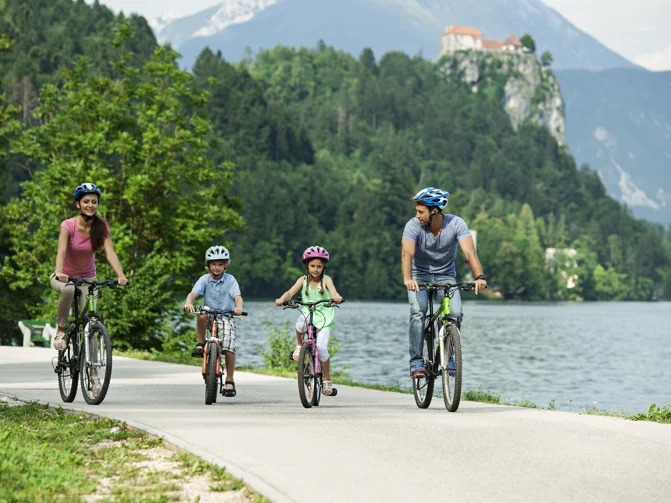 Štiričlanska družina na kolesu veselo kolesari ob blejskem jezeru
