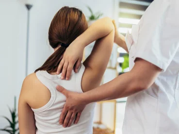 Zdravnik med rehabilitacijo pregleduje pacientkino držo in njen hrbet