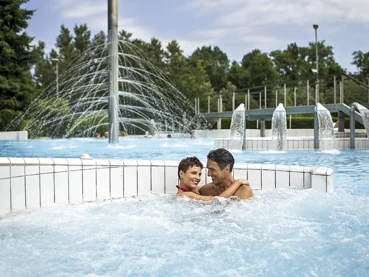 Par v srednjih letih sproščeno uživa v vodi zunanjega bazena in se objema