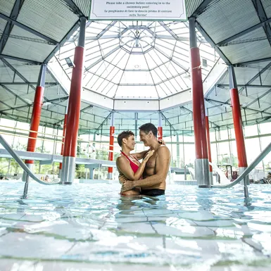 Par se zaljubljeno gleda in objema na sredini notranjega bazena