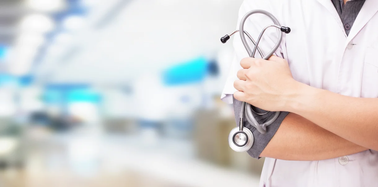 Zdravnik v beli halji stoji s stetoskopom v roki