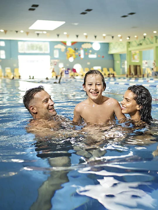 Tričlanska družina se zabava v notranjem plavalnem bazenu