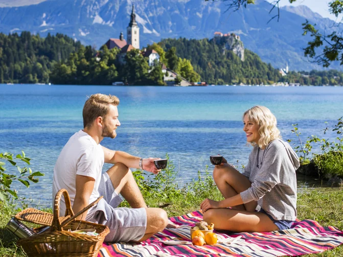 Mlajši par sproščeno uživa na pikniku ob Blejskem jezeru