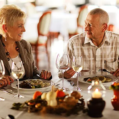 Par v starejših letih sedi za obloženo mizo in ob sveči večerja