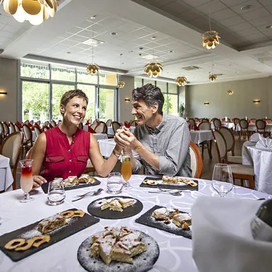 Moški in ženska sedita za polno mizo dobrot v hotelski restavraciji in se pogovarjata