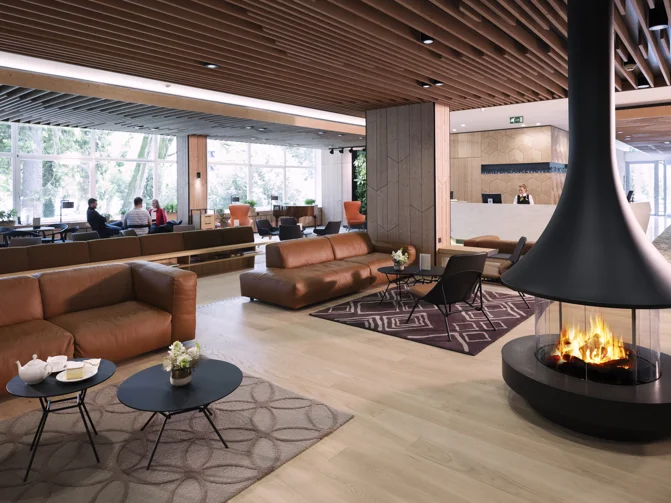 Sodobno urejen predprostor v hotelu s kaminom, usnjenimi fotelji, mizicami ter kavarno v ozadju