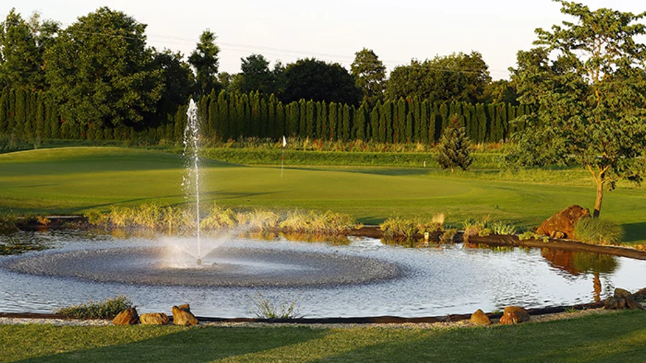 Pogled na sproščujočo vodno fontano ob zelenem golf igrišču