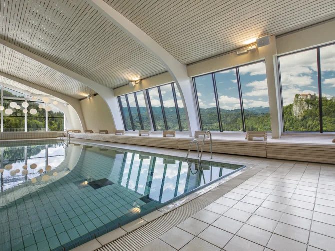 Notranji termalni bazen in leseni ležalniki s pogledom na otok sredi Blejskega jezera