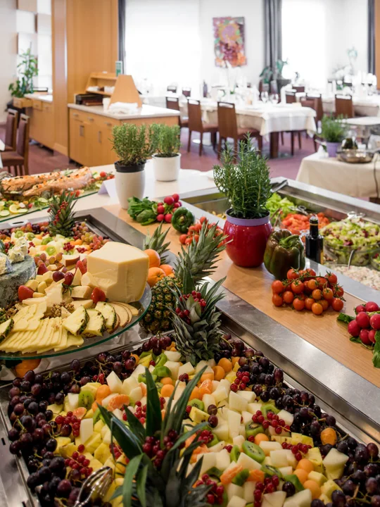 Hotelski samopostrežni brunch, ki vsebuje veliko različnih jedi: sirno ploščo, mesne dobrote, sadje in zelenjavo