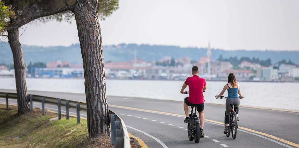 Moški in ženska kolesarita na kolesarski potki ob morju