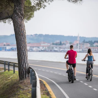 Moški in ženska kolesarita na kolesarski potki ob morju