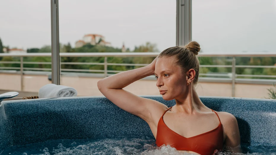 Ženska v rdečih kopalkah uživa v vročem termalnem bazenu z mehurčki