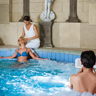 Moški in ženska se objemata in uživata v masažnem bazenu ob svečah