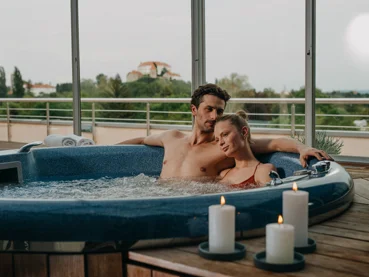 Moški in ženska se objemata in uživata v masažnem bazenu ob svečah