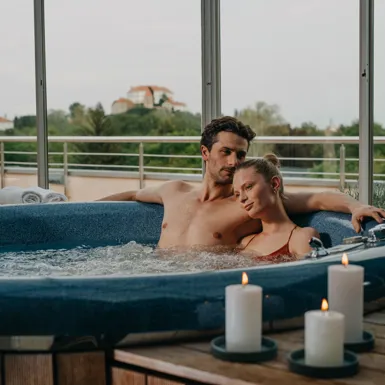 Moški in ženska se objemata in uživata v masažnem bazenu ob svečah