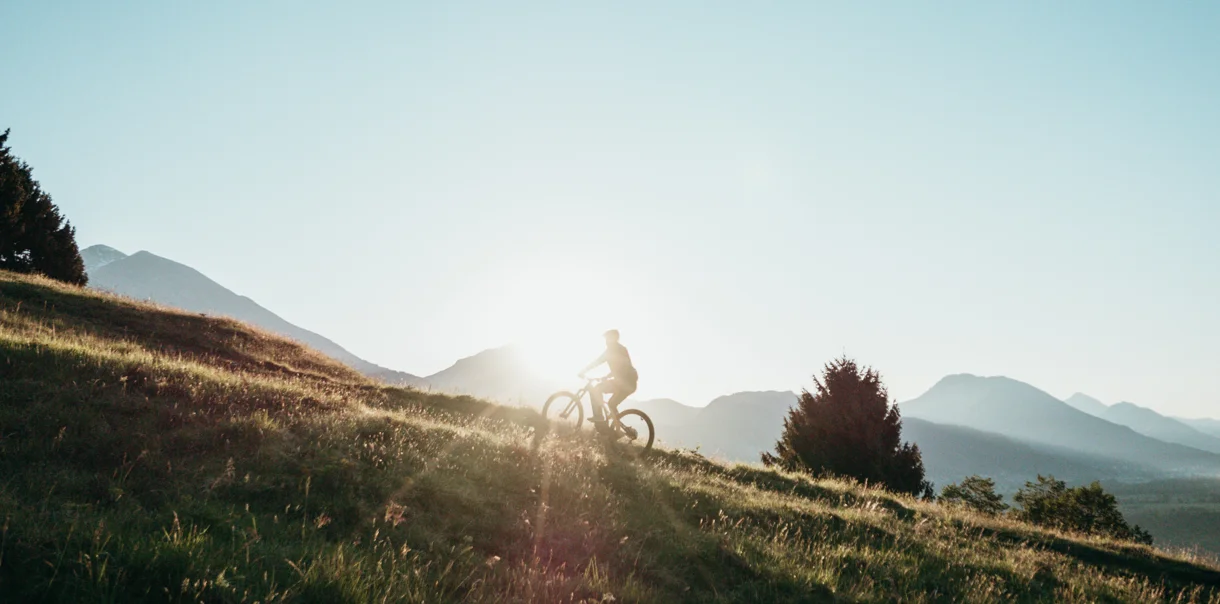 Kolesar kolesari na vzponu po gozdnih poteh z okoliškimi gorami v ozadju