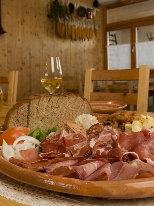 Miza, na kateri so lesen pladenj z okusnim mesnim narezkom in nekaj kozarcev vina