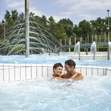 Par v srednjih letih sproščeno uživa v vodi zunanjega bazena in se objema