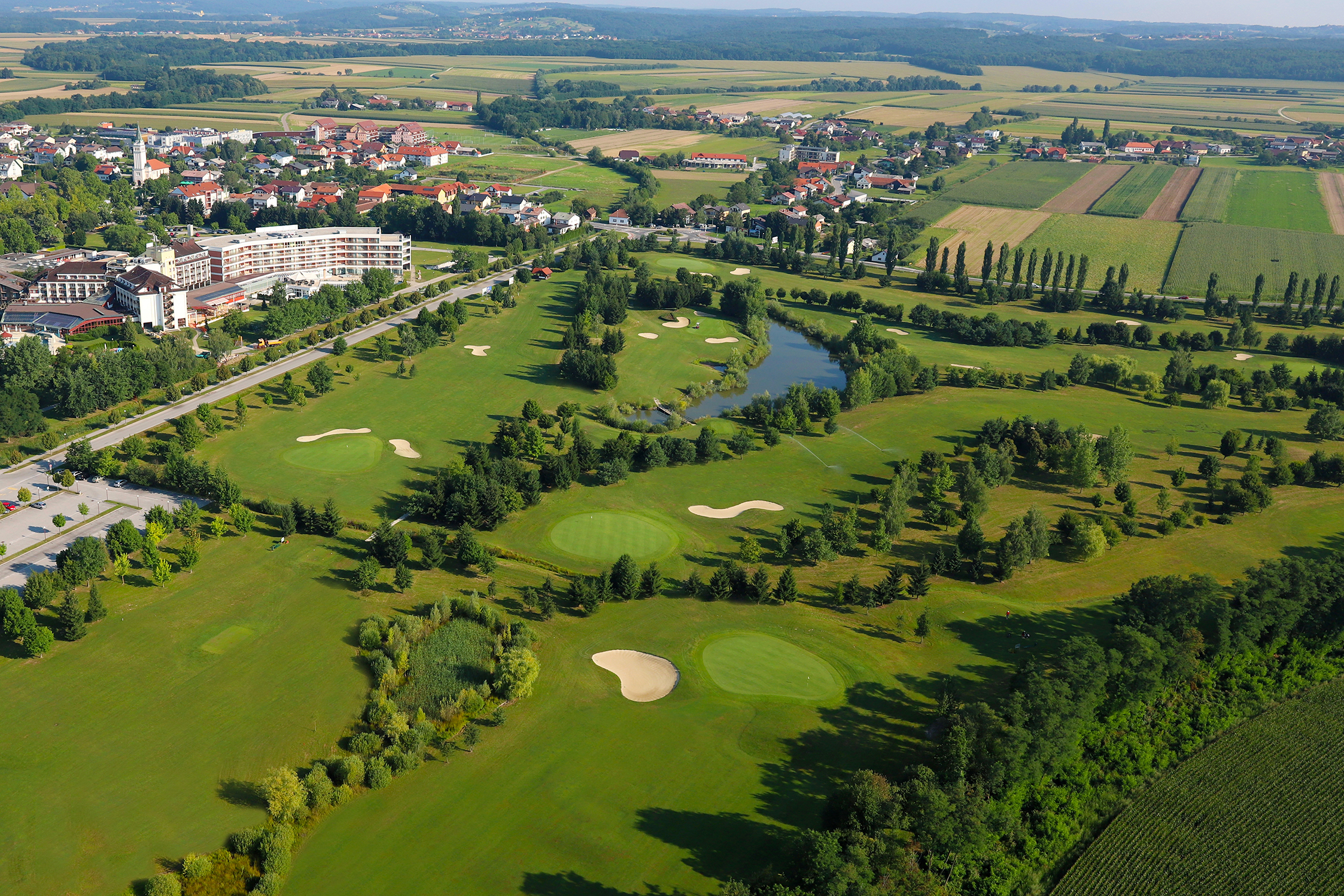 Prekrasen pogled na zeleno travnato površino golf igrišč, gozda, jezera, hotelskega kompleksa in mesta
