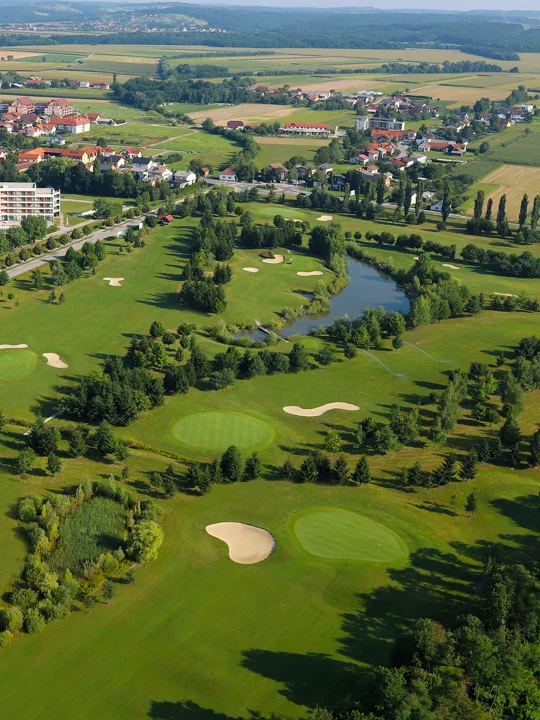 Prekrasen pogled na zeleno travnato površino golf igrišč, gozda, jezera, hotelskega kompleksa in mesta