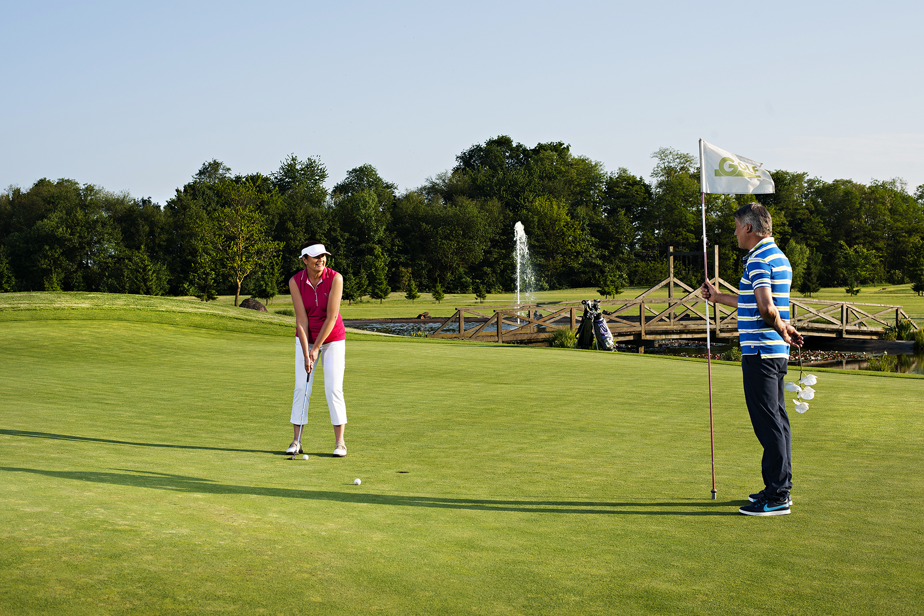 Moški in ženska v športnih oblačilih igrata golf na golf igrišču