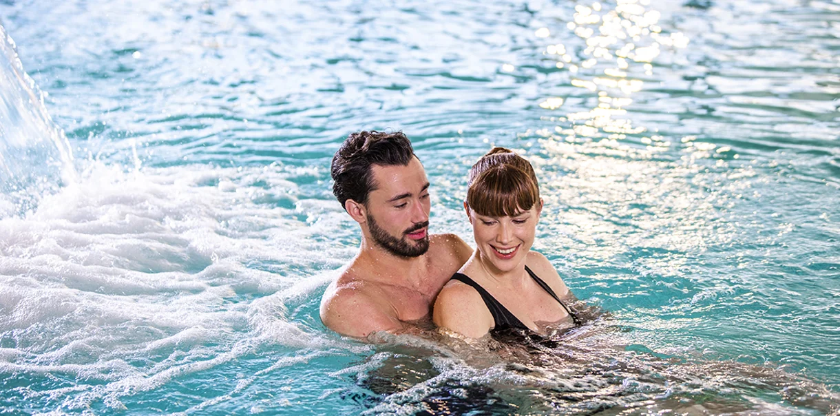 Moški in ženska se objemata in uživata v notranjem termalnem bazenu