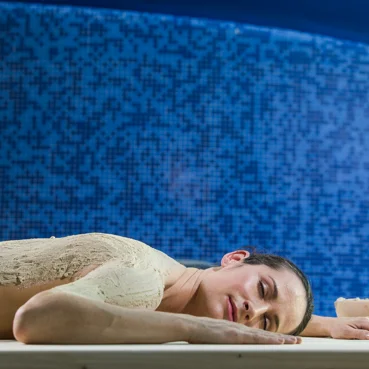 Ženska leži na trebuhu, po hrbtu pa je namazana z blatom za namen sproščujoče masaže